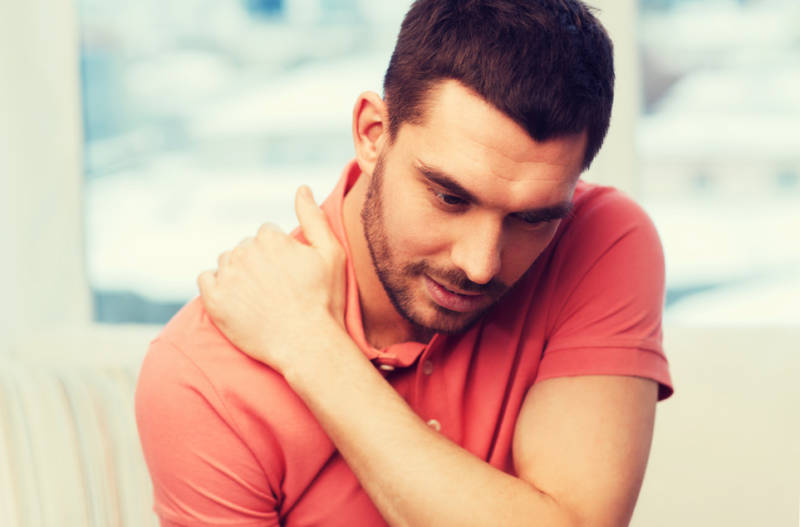 unhappy man suffering from neck pain at home